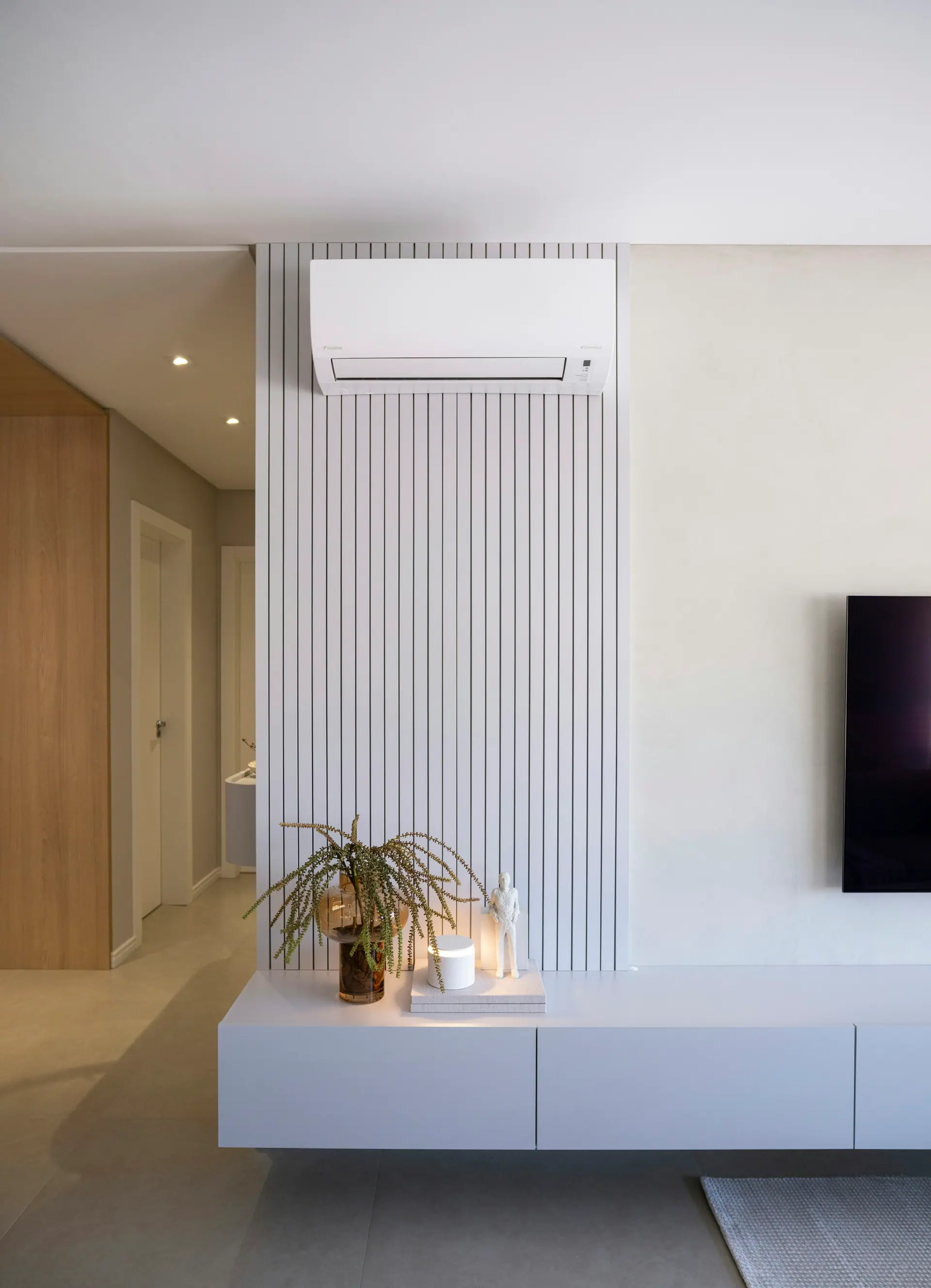 Wall-mounted split air conditioner above a sofa in a bright living room