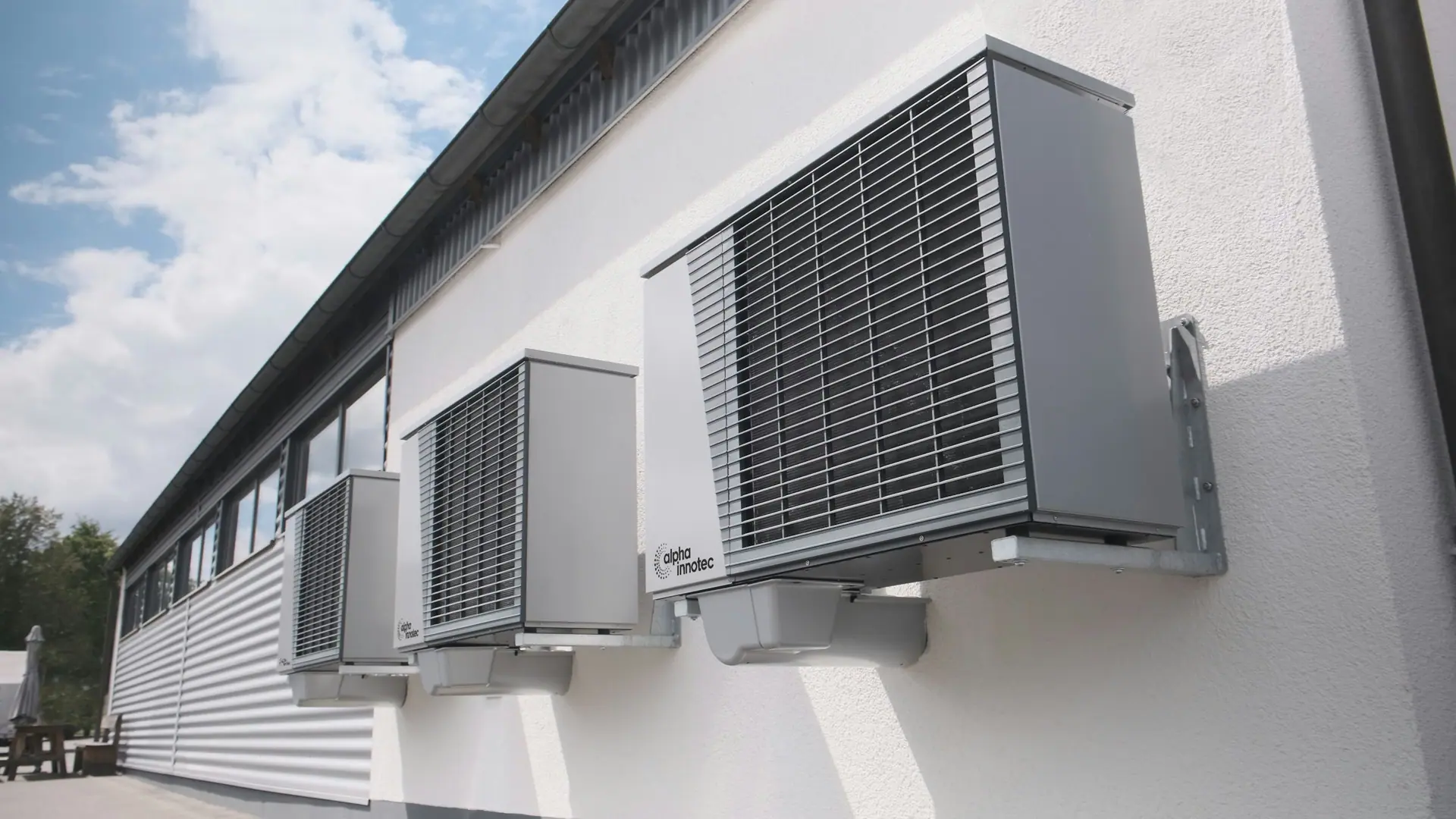 Large outdoor air conditioning units fixed to a white building wall