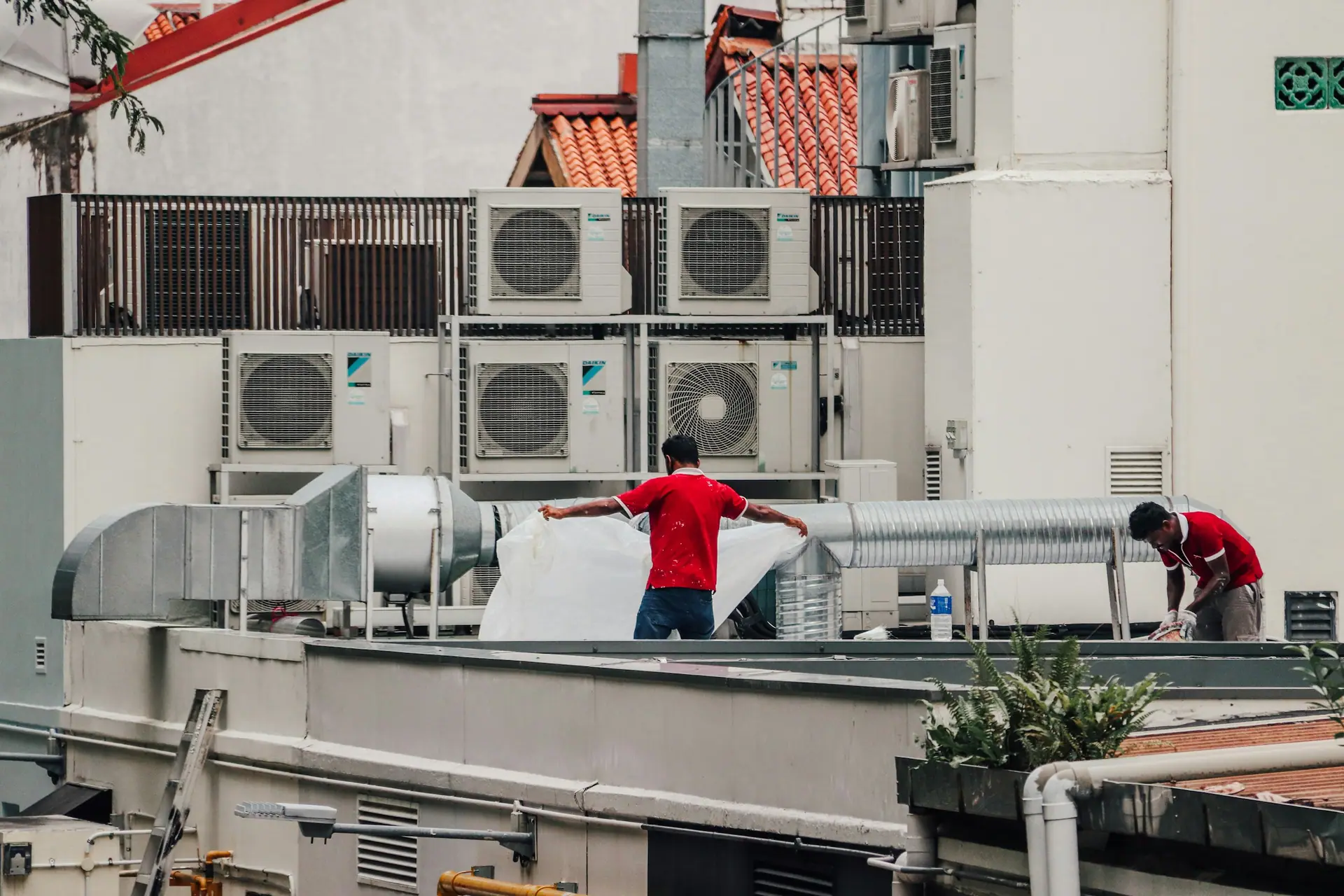 Technicians working among rooftop air conditioning plant and ducting